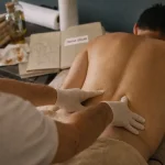 Massage hernie discale : praticien masse le bas du dos pour soulager la douleur